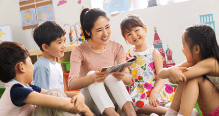 A kindergarten educator teaching a group of young children after graduating with a diploma in education in WOU.